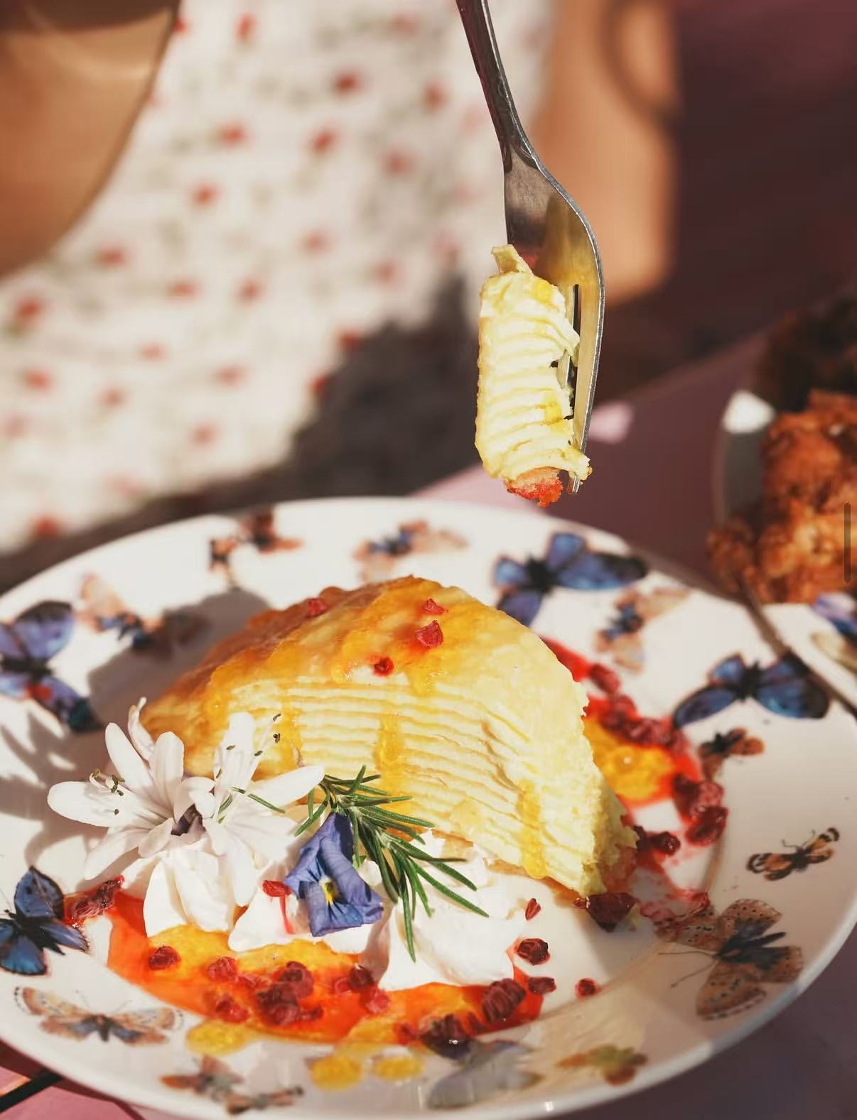Layered dessert plated with flowers and sauce