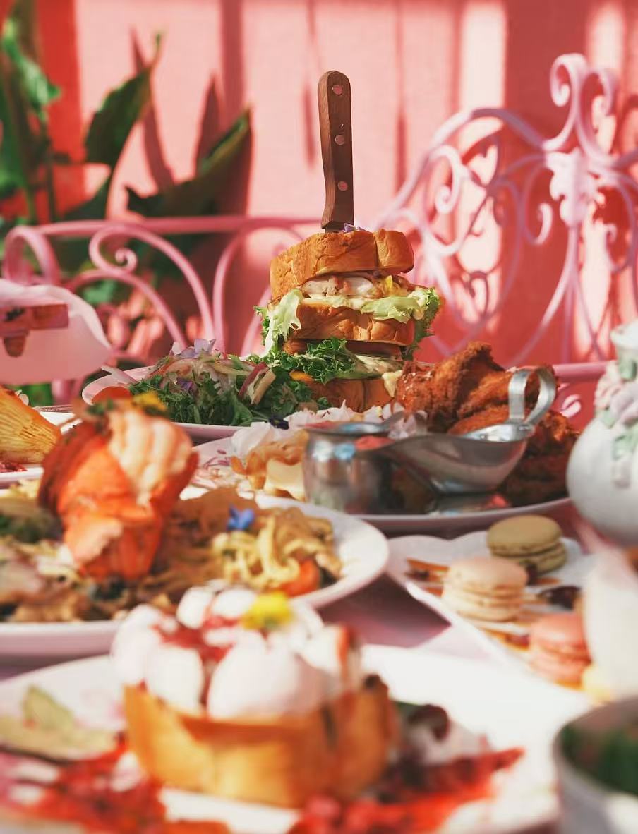 Restaurant table spread with sandwich, lobster, dessert, and tea service