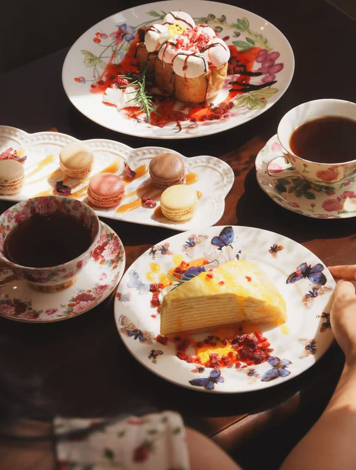 Desserts, tea cups, macarons, and plated cake on a table